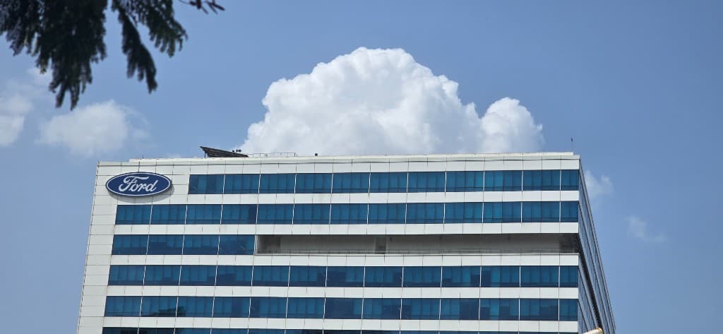 Ford office building with Ford logo against a blue sky and white cloud